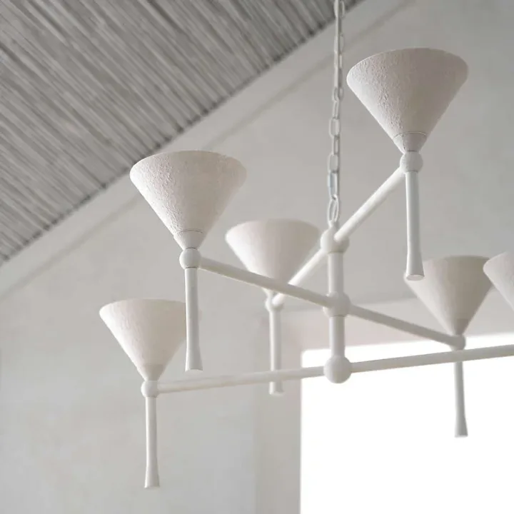 A white plaster chandelier with six cone shades, its finish rough rather than glossy