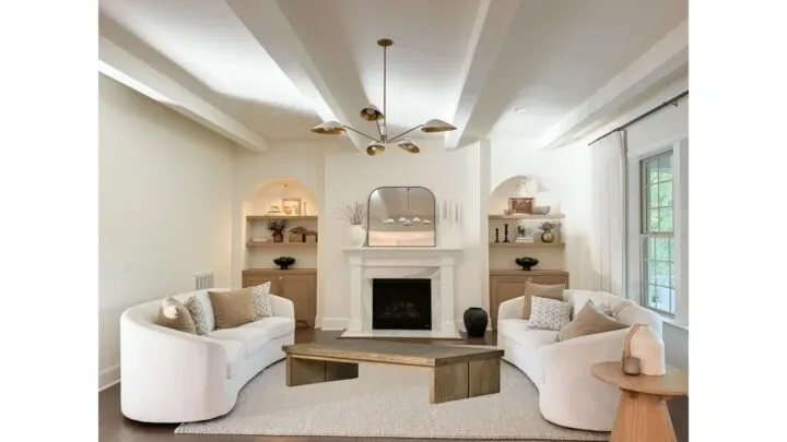 A low rectangular wood coffee table between the two curved cream sofas
