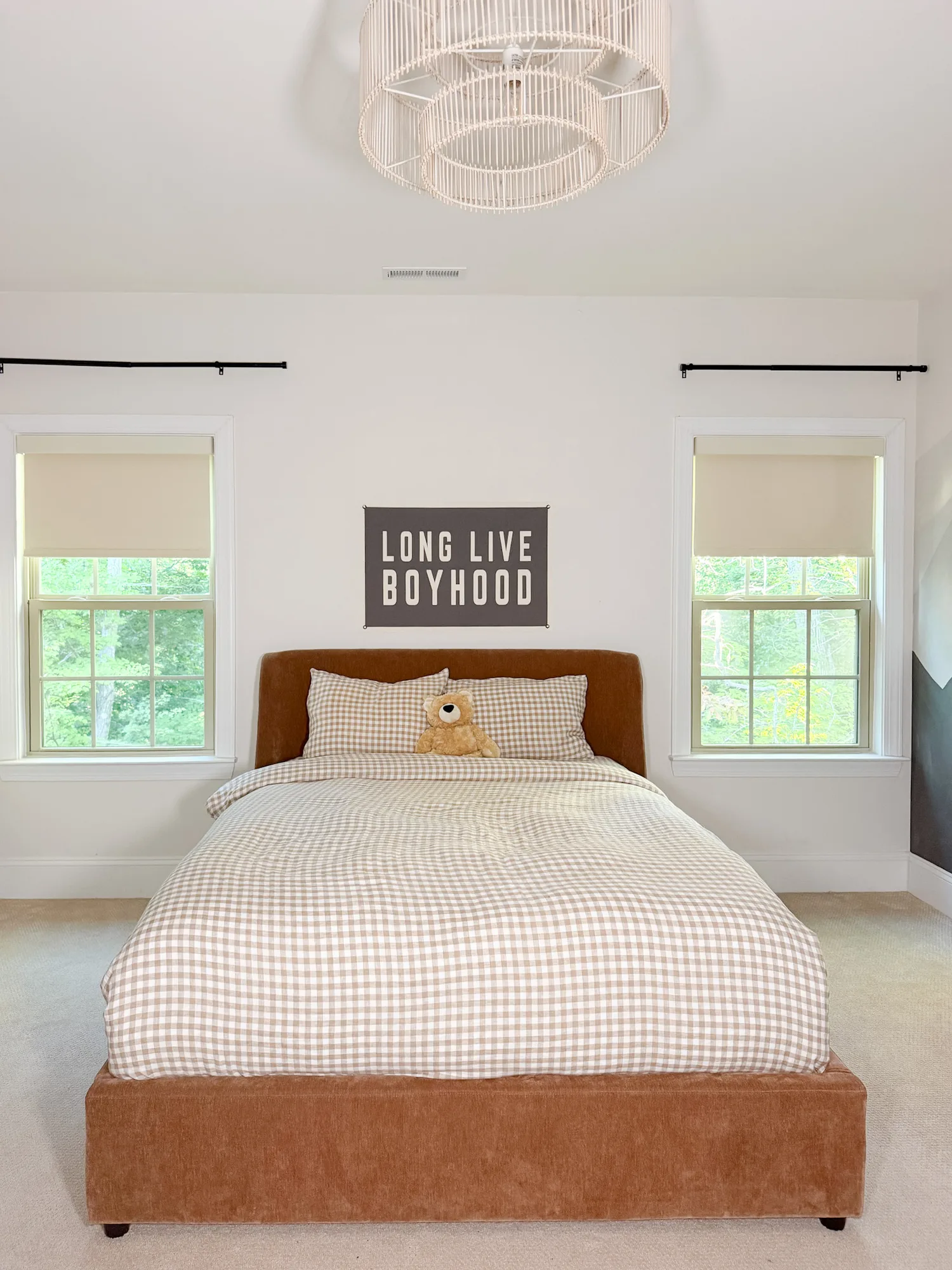 Two cream Freshine motorized roller shades above a brown bed with gingham bedding in a boy’s bedroom
