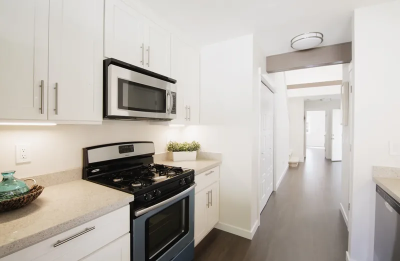 Looking down the narrow galley past the gas range and microwave to the hallway beyond