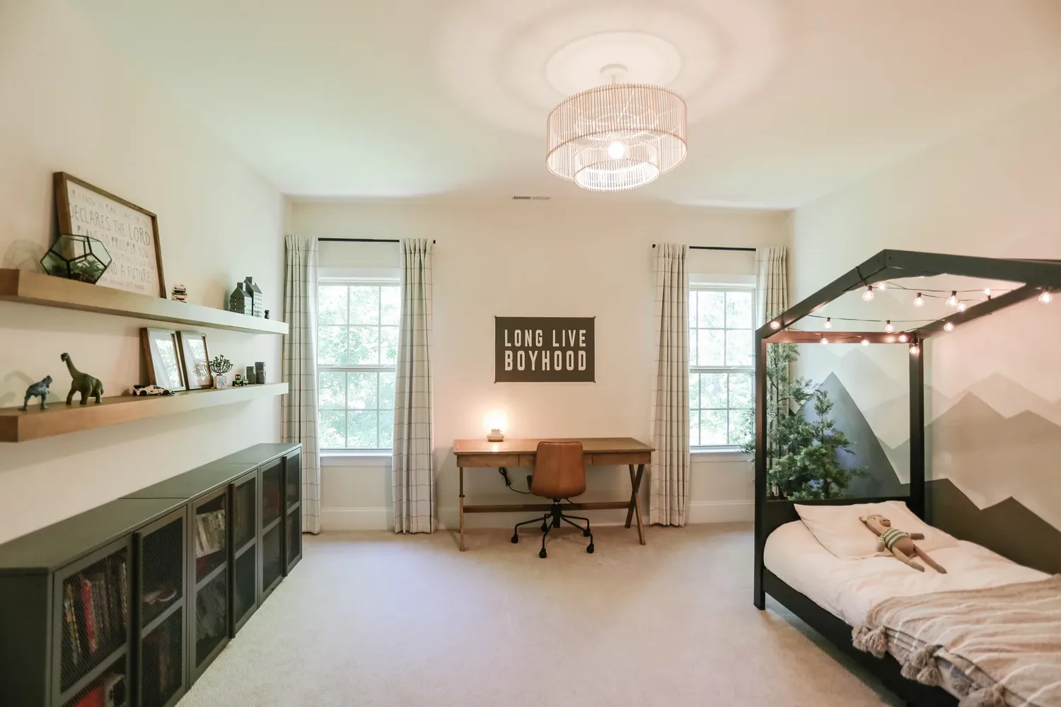 Wide view of the whole boys' room: storage wall left, desk between two windows, house bed right