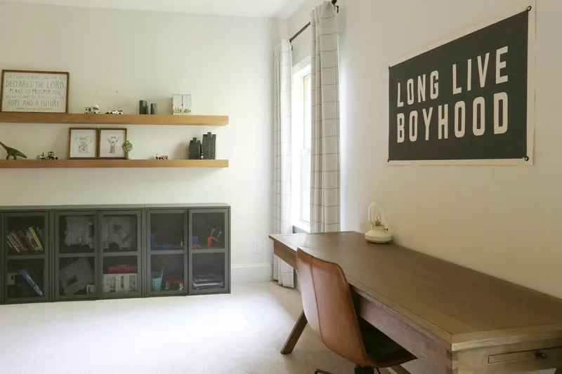 Down the length of the desk toward the toy cabinets, the banner on the wall above