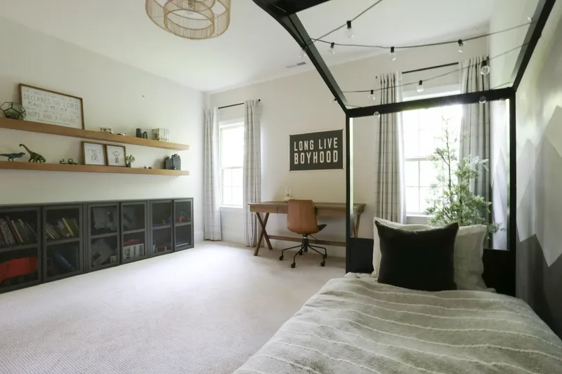 Past the string lights from the head of the bed, the desk and shelves across the room