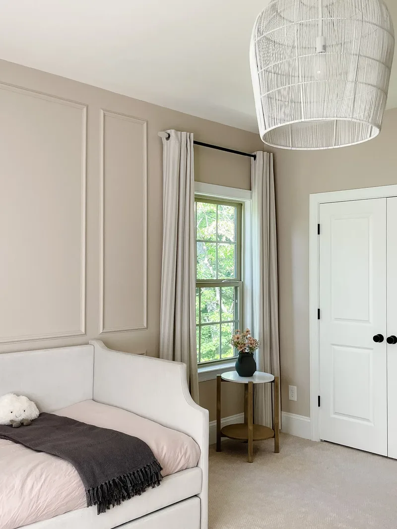 The far corner of the room — curtained window, marble-topped brass side table and white closet doors