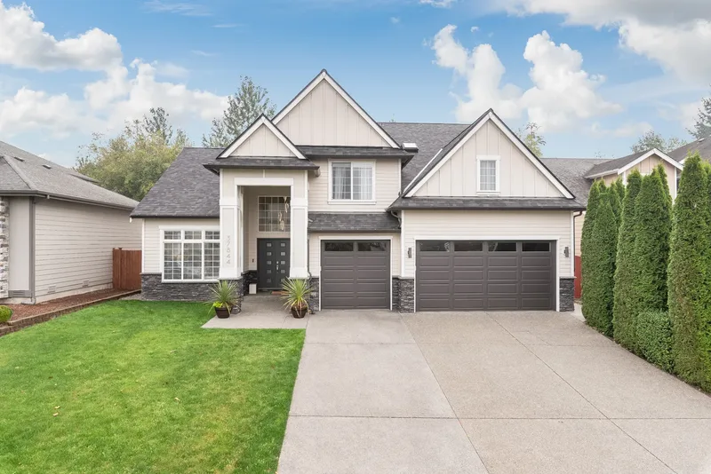 The remodelled house from the street, board-and-batten gables, stone skirt and two dark garage doors