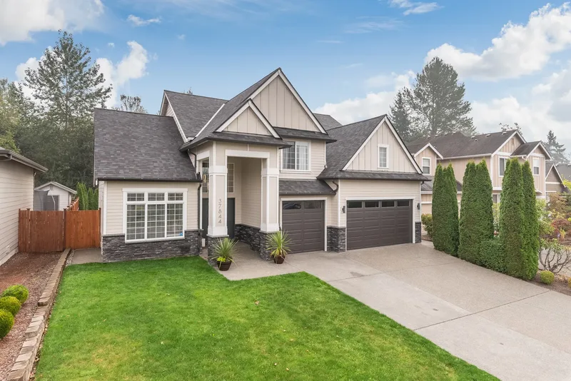 The elevation from beside the driveway, columned entry porch and tall arborvitae along the property line