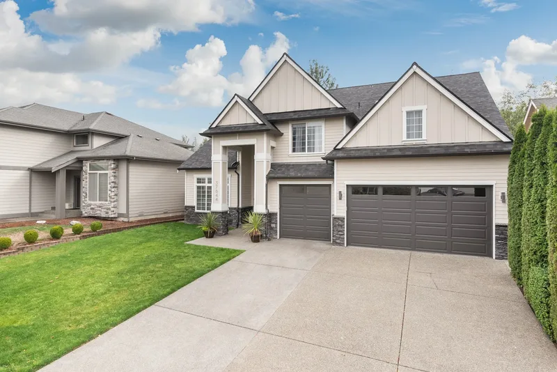 A three-quarter view across the wide concrete driveway to the garage doors and gabled roofline