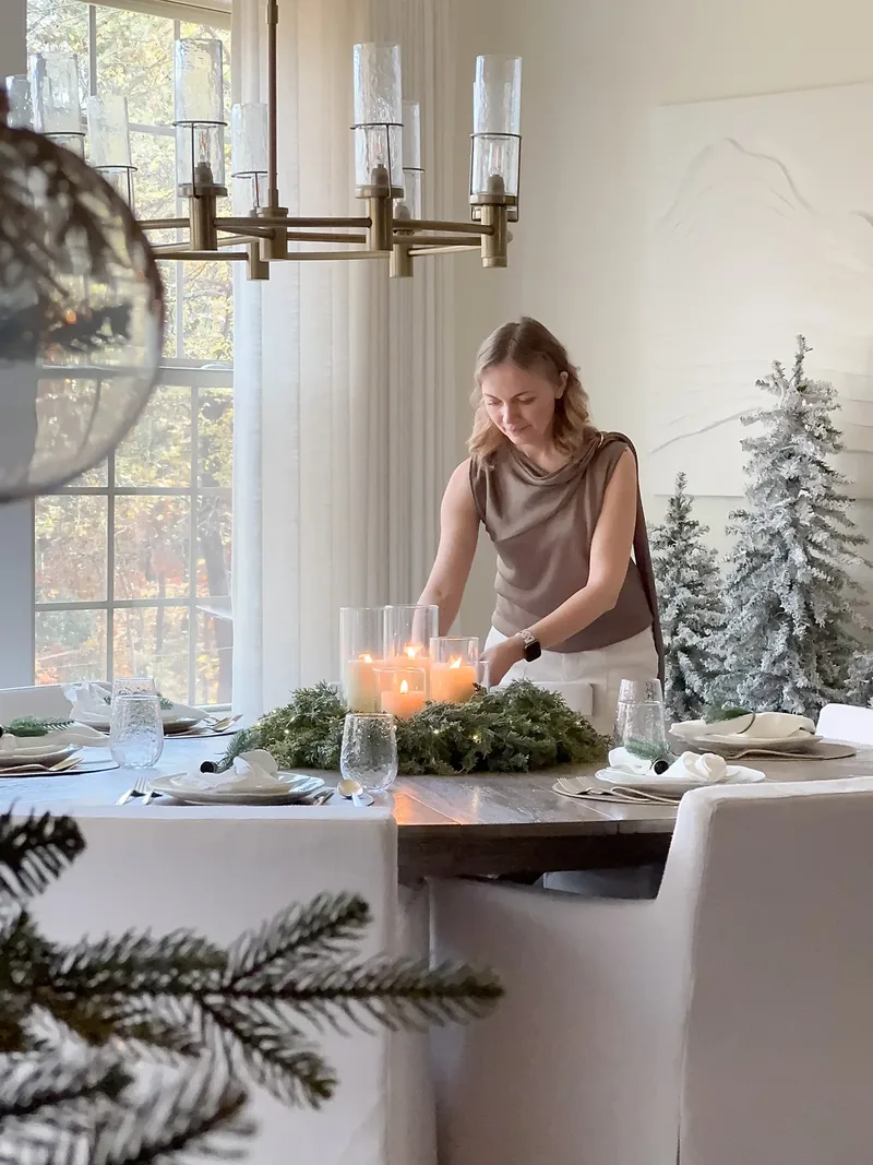 Candles glowing inside a fir wreath centrepiece as Tatyana lights them, flocked trees in the corner