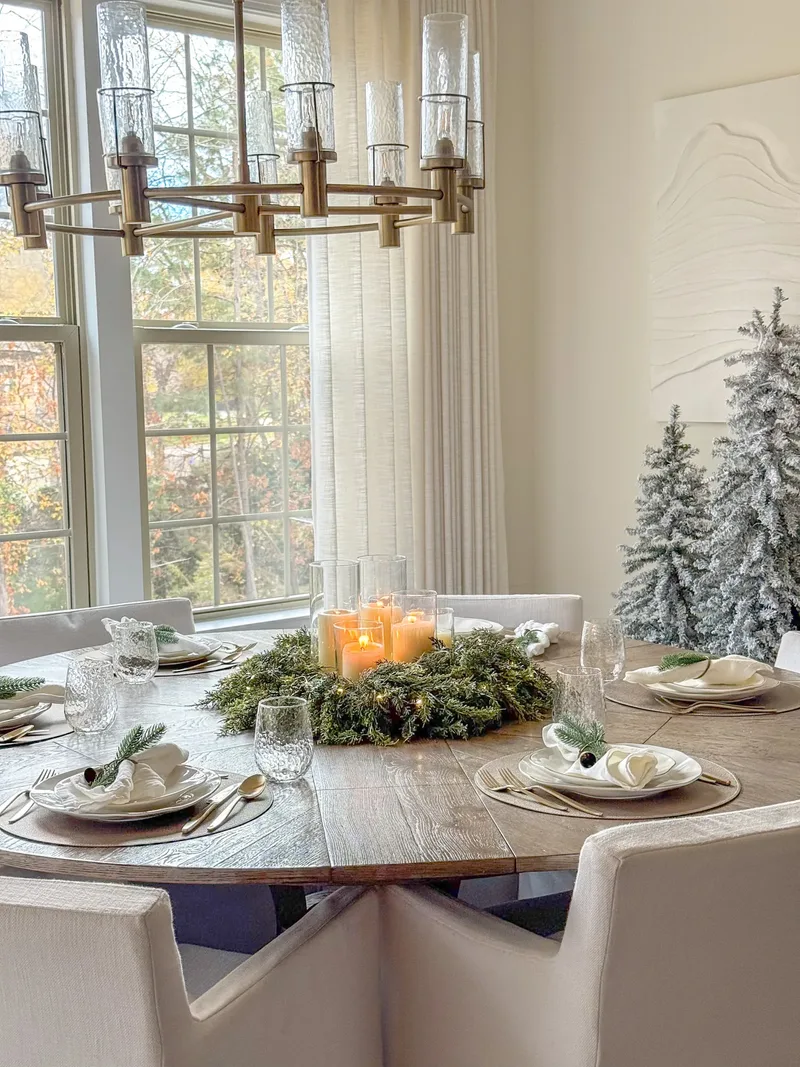 Wreath candles glowing on the round table beneath the tall windows, seen from further back