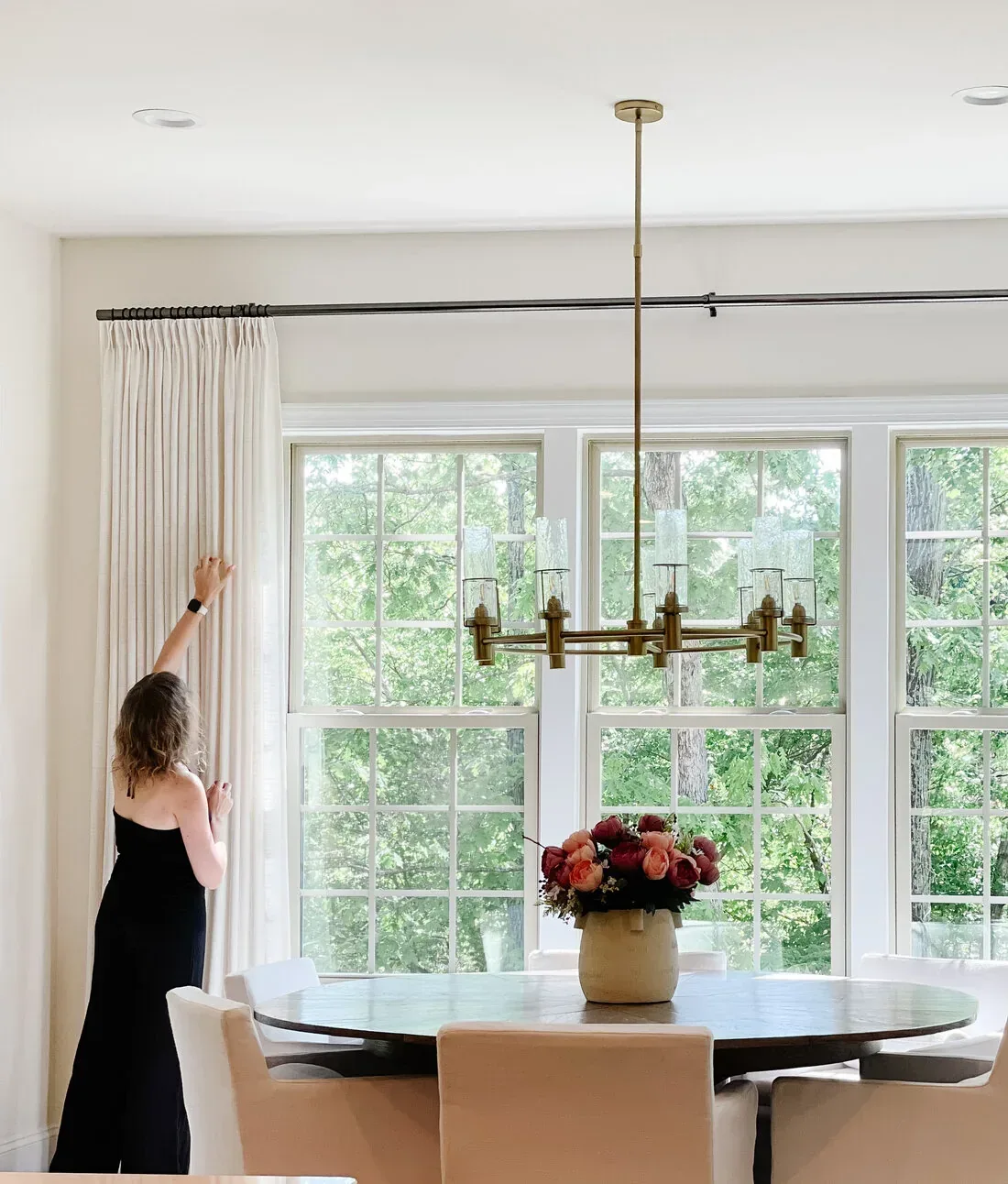 Tatyana adjusting drapery in a finished dining room