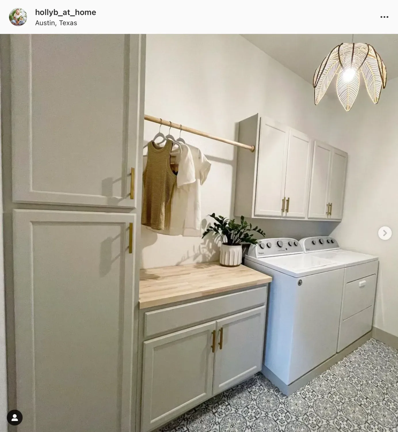 A laundry room in Accessible Beige cabinetry with a butcher-block counter and a brass hanging rail