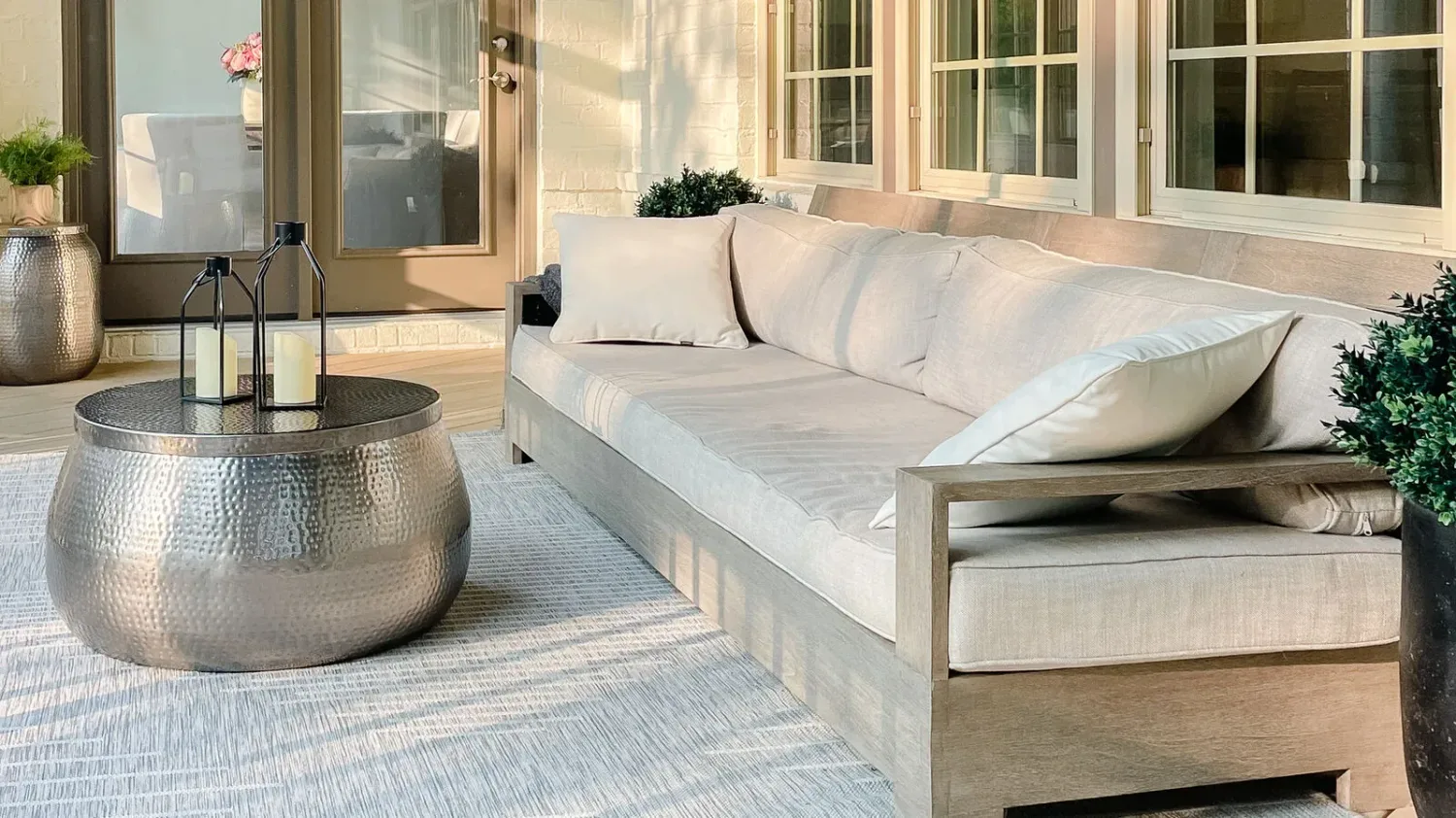 Covered porch with a daybed, layered textiles and glass doors