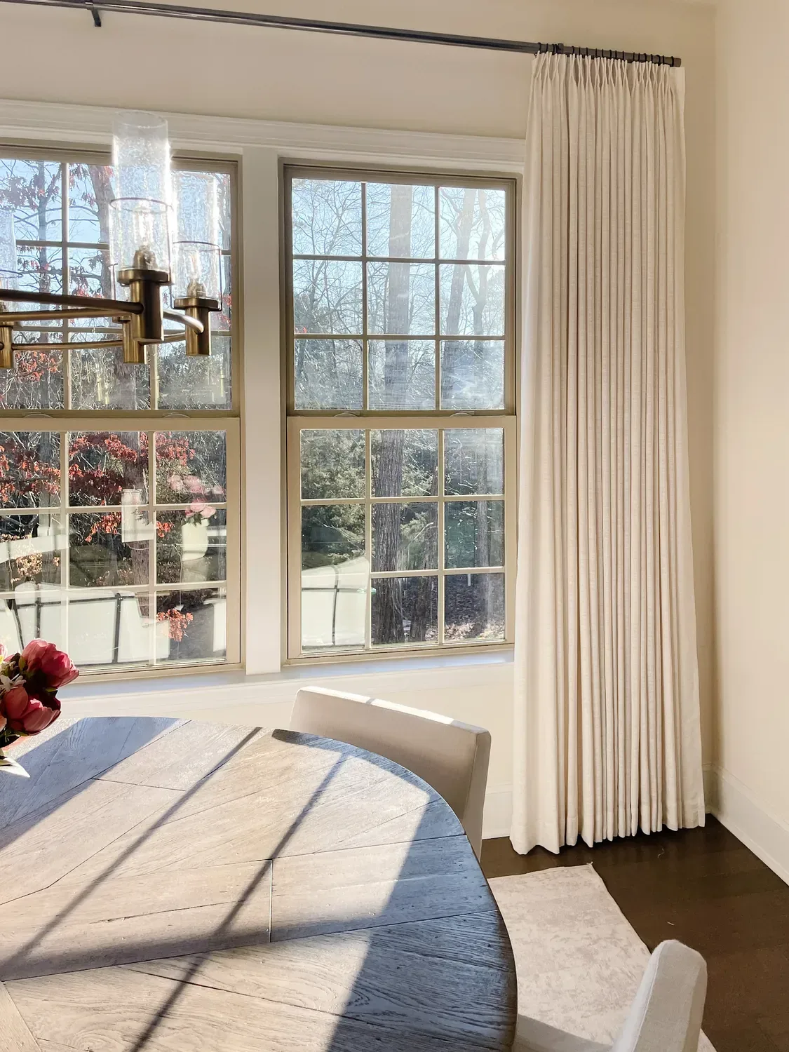 An ivory pinch pleat panel hung to the ceiling beside the dining room's windows