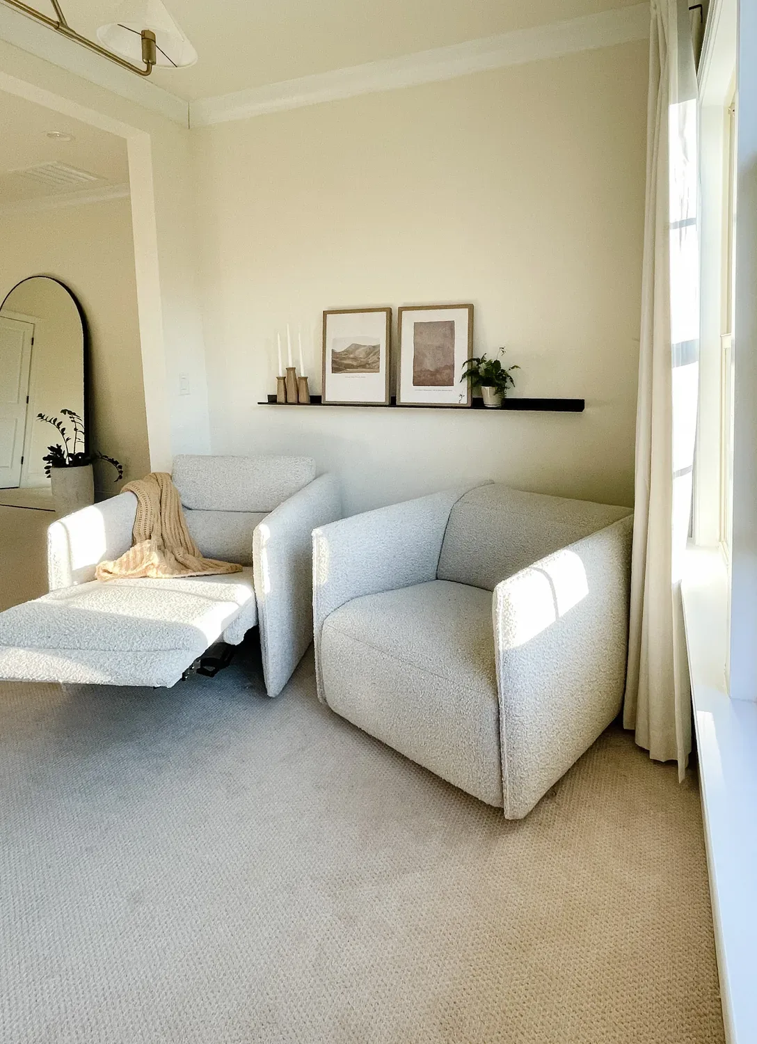 Two pale boucle recliners by a window, one reclined with its footrest out