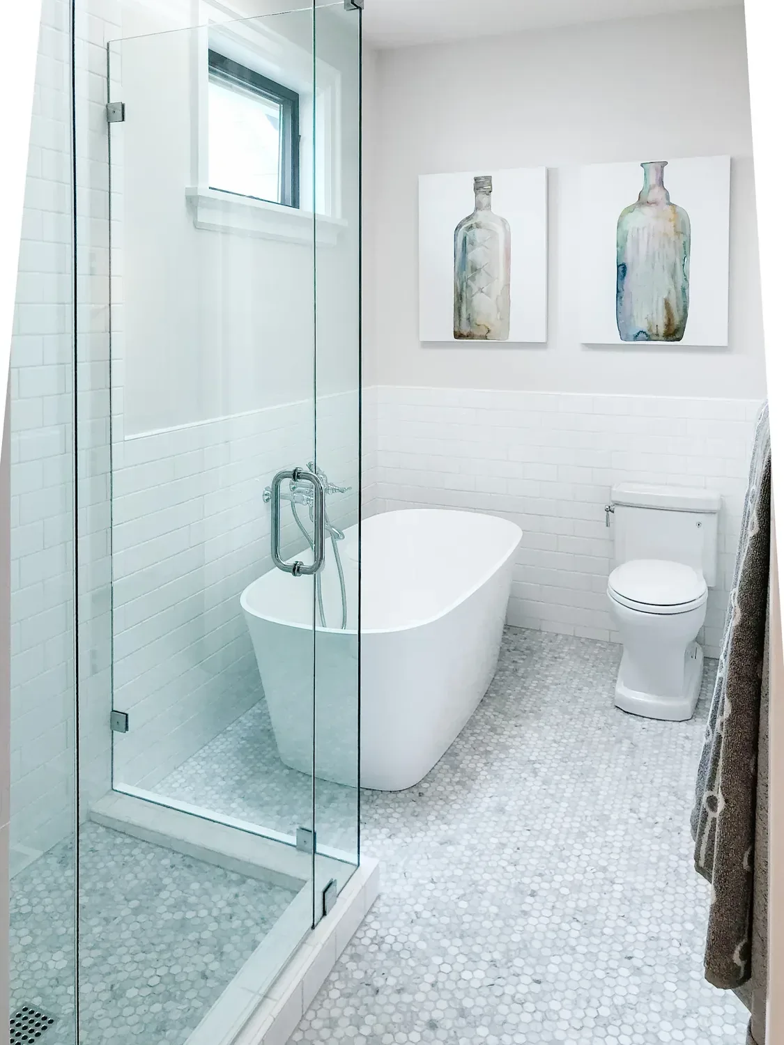 A freestanding tub beside a glass shower, subway-tiled walls and a marble hex mosaic floor
