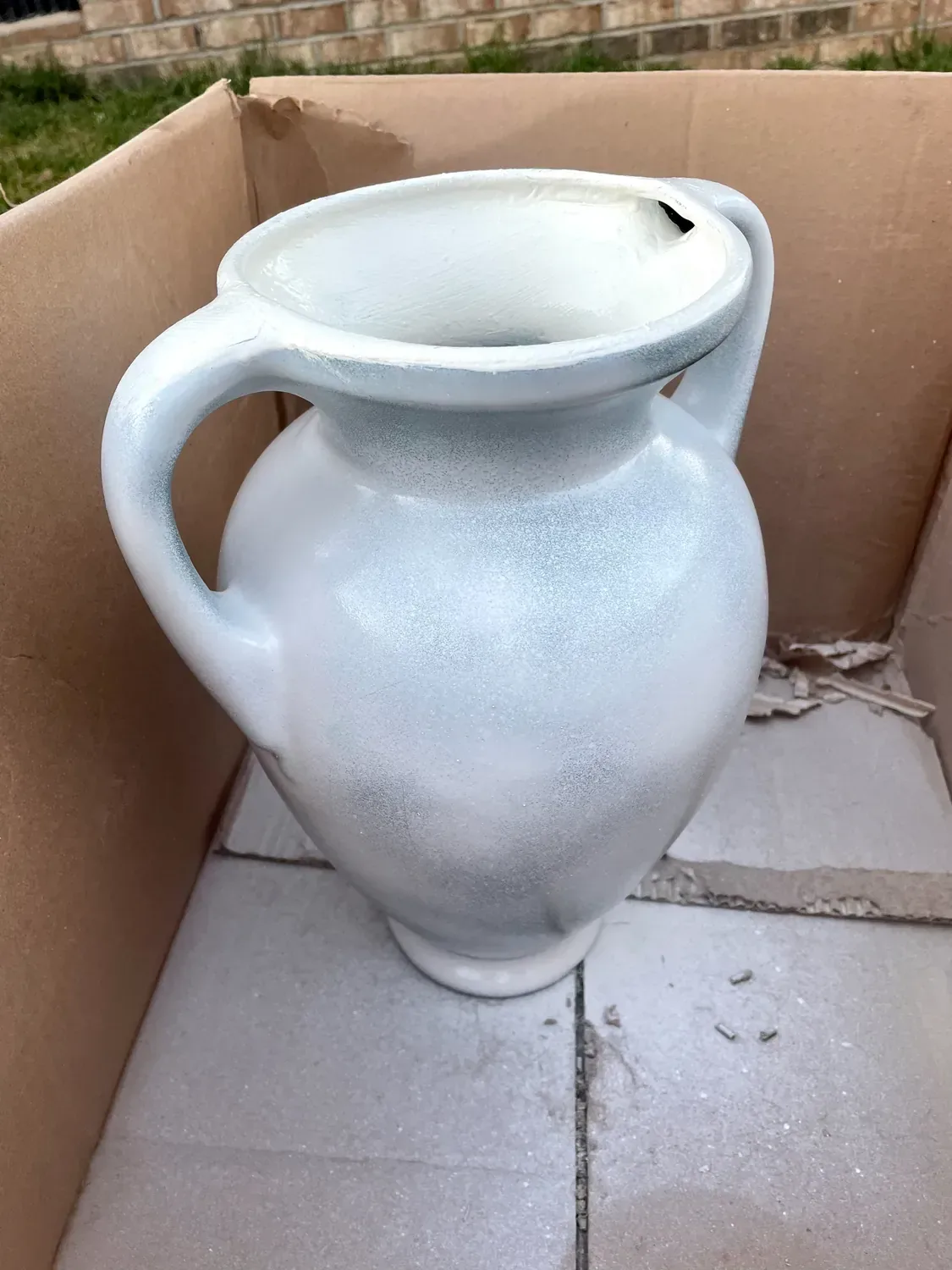 The vase spray-primed white inside a cardboard box, the green still showing through