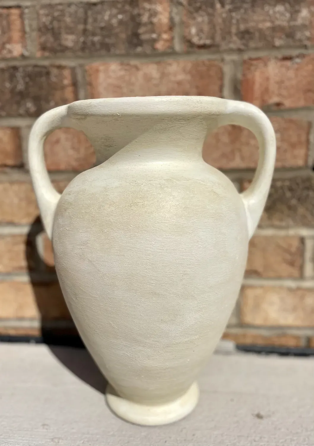 The finished vase in chalky cream with a weathered, aged-pottery surface