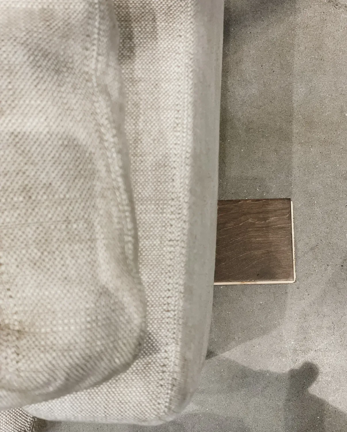 A wood sample set on the floor beside a cream linen sofa corner