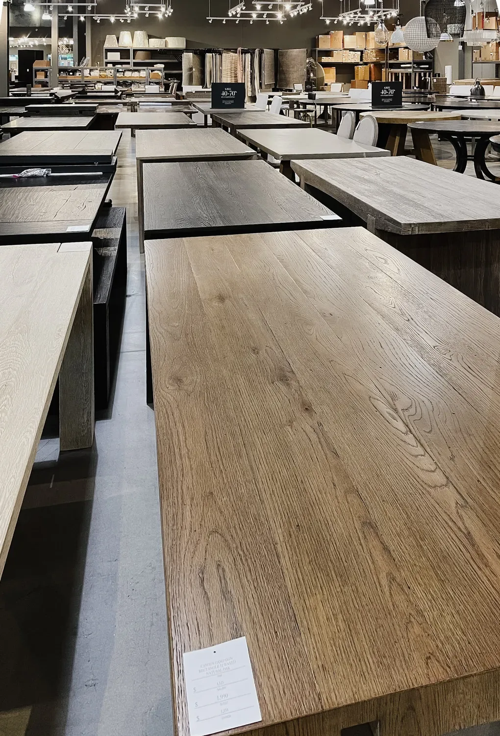 Rows of near-identical wooden dining tables filling the outlet showroom floor
