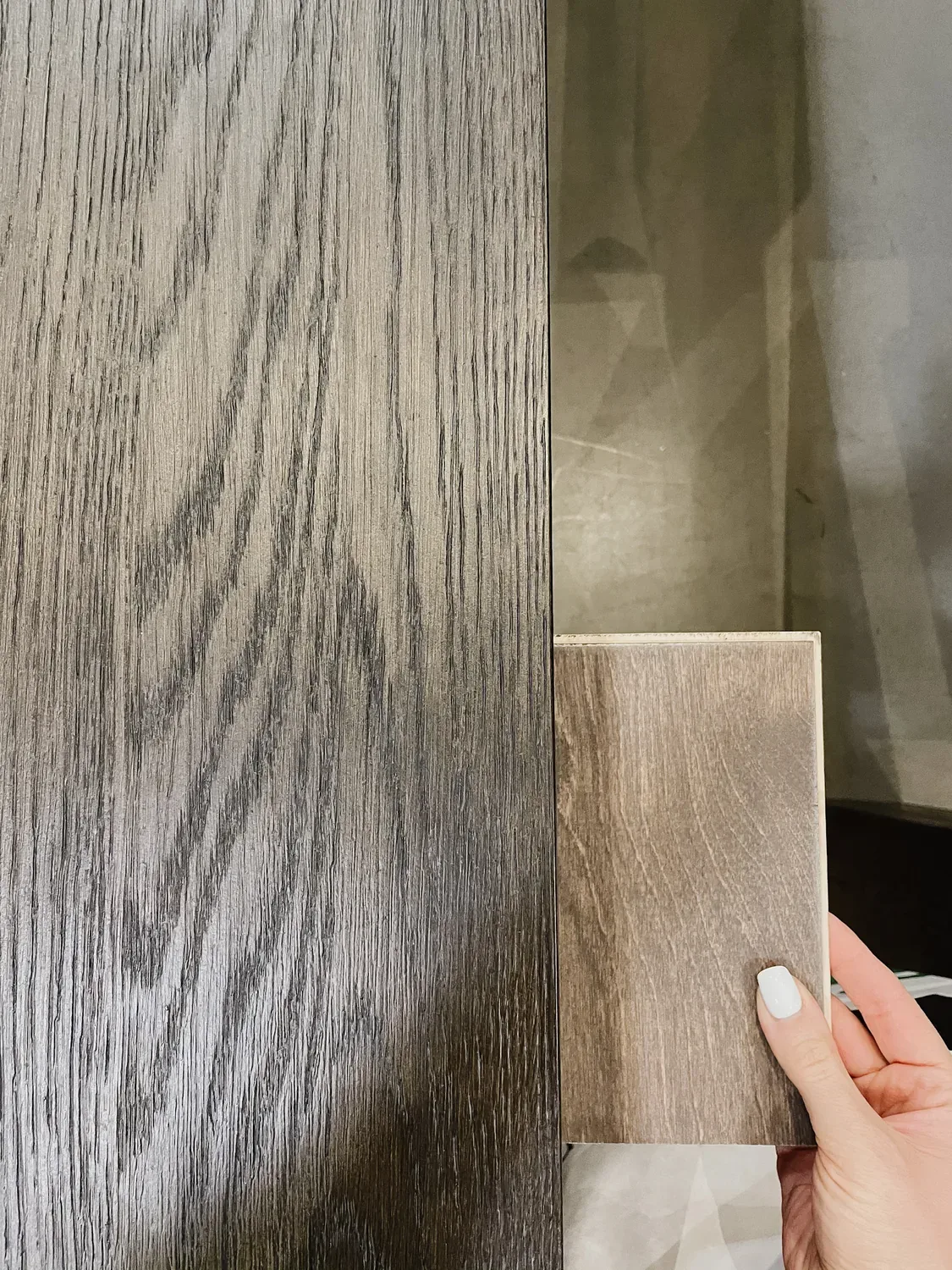 A wood sample held beside a grey-washed oak top, the grain of each side by side