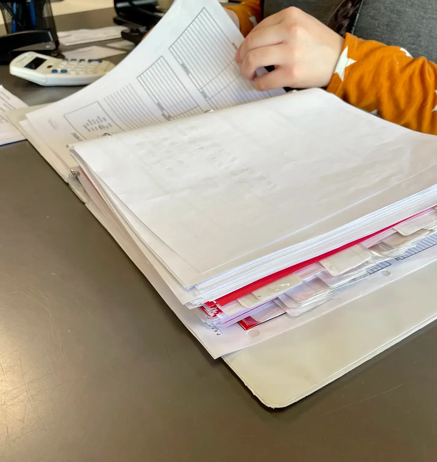 A sales assistant leafing through the outlet's binder of inventory sheets