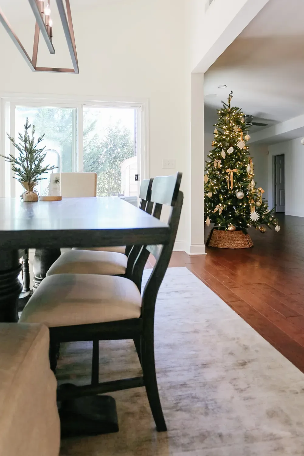The dining room after: a black table and upholstered chairs under a lantern chandelier