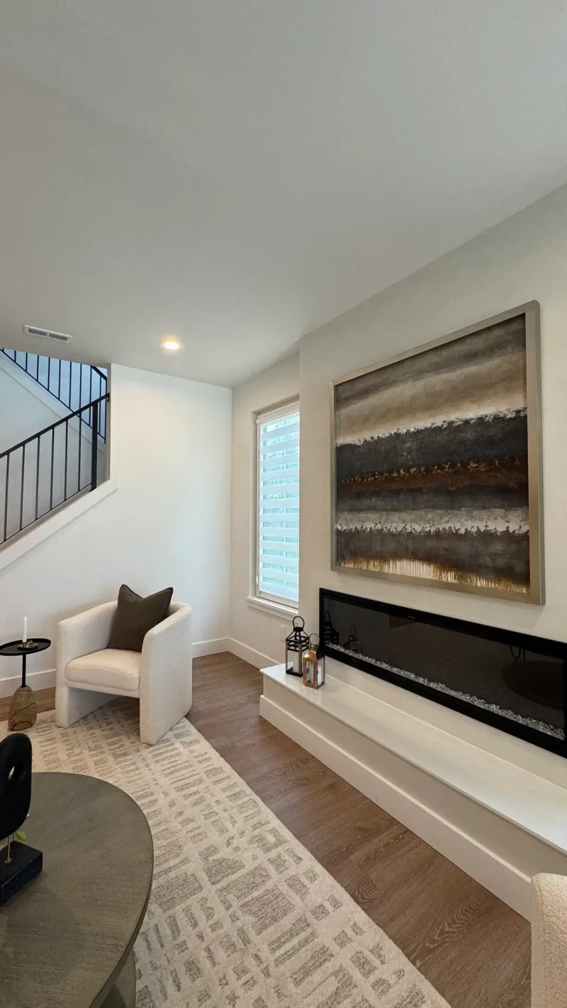 Sitting area with a long linear fireplace and an abstract landscape hung above it