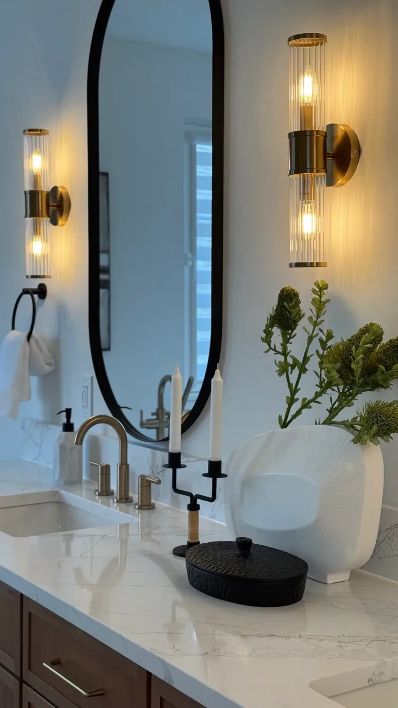 Vanity detail: an oval black mirror between fluted brass sconces