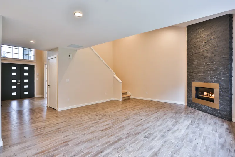 Living room looking back to the front door and stairs, floor-to-ceiling stone fireplace with a linear gas insert