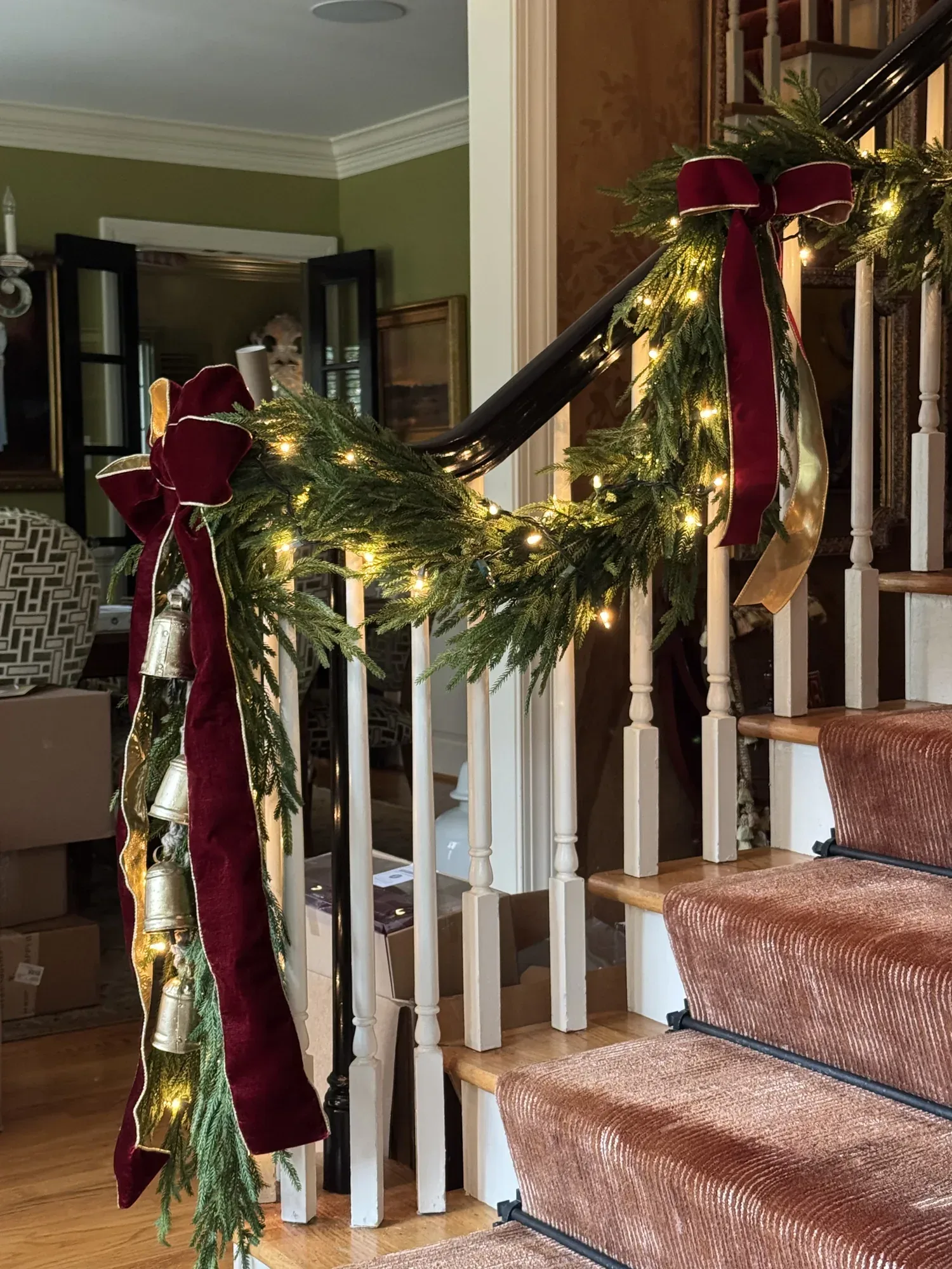 Staircase garland with burgundy velvet bows and warm lights along the rail