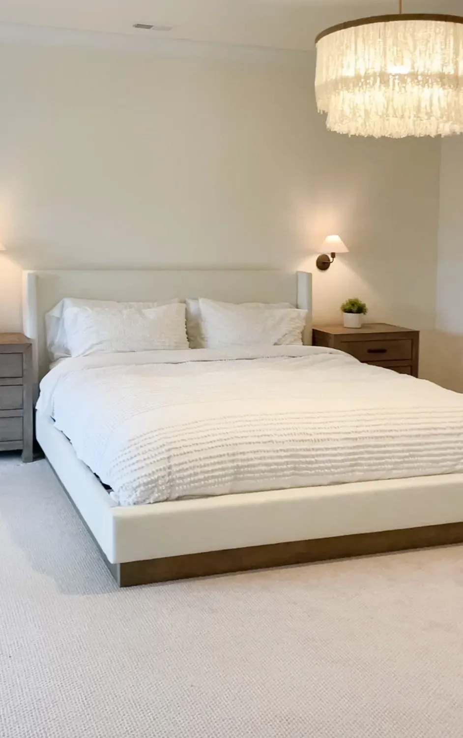 The bed made up in plain white bedding against the cream upholstered headboard