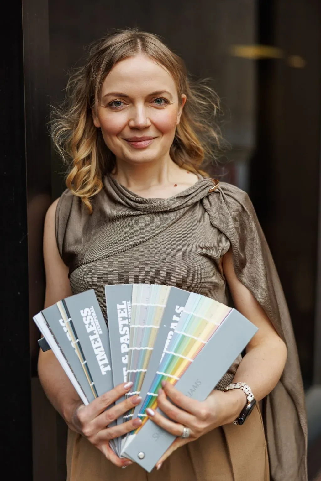 Tatyana holding a fan of paint decks in a doorway