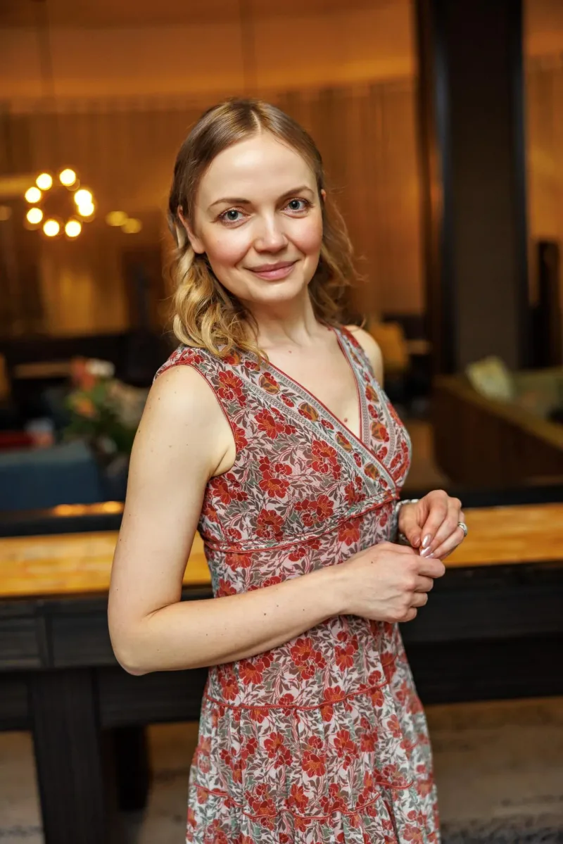 Tatyana in a red floral dress, in a warm restaurant interior