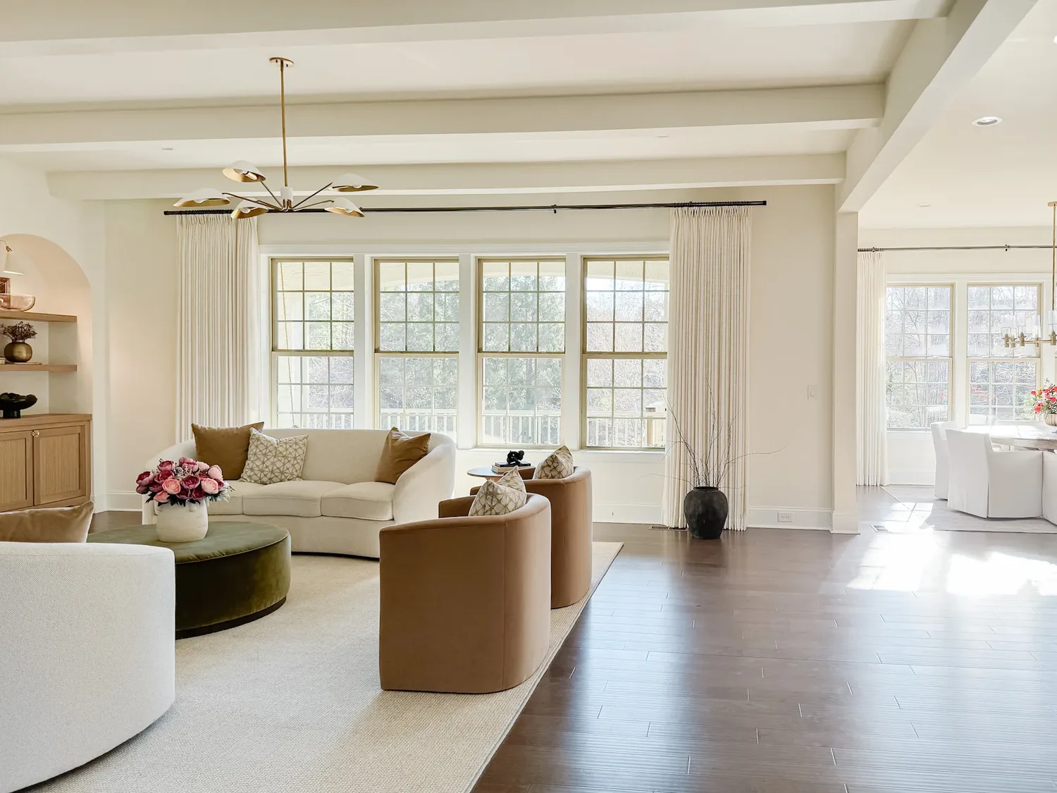 The seating group from the far corner, beamed ceiling and brass chandelier above sunlit wood floors