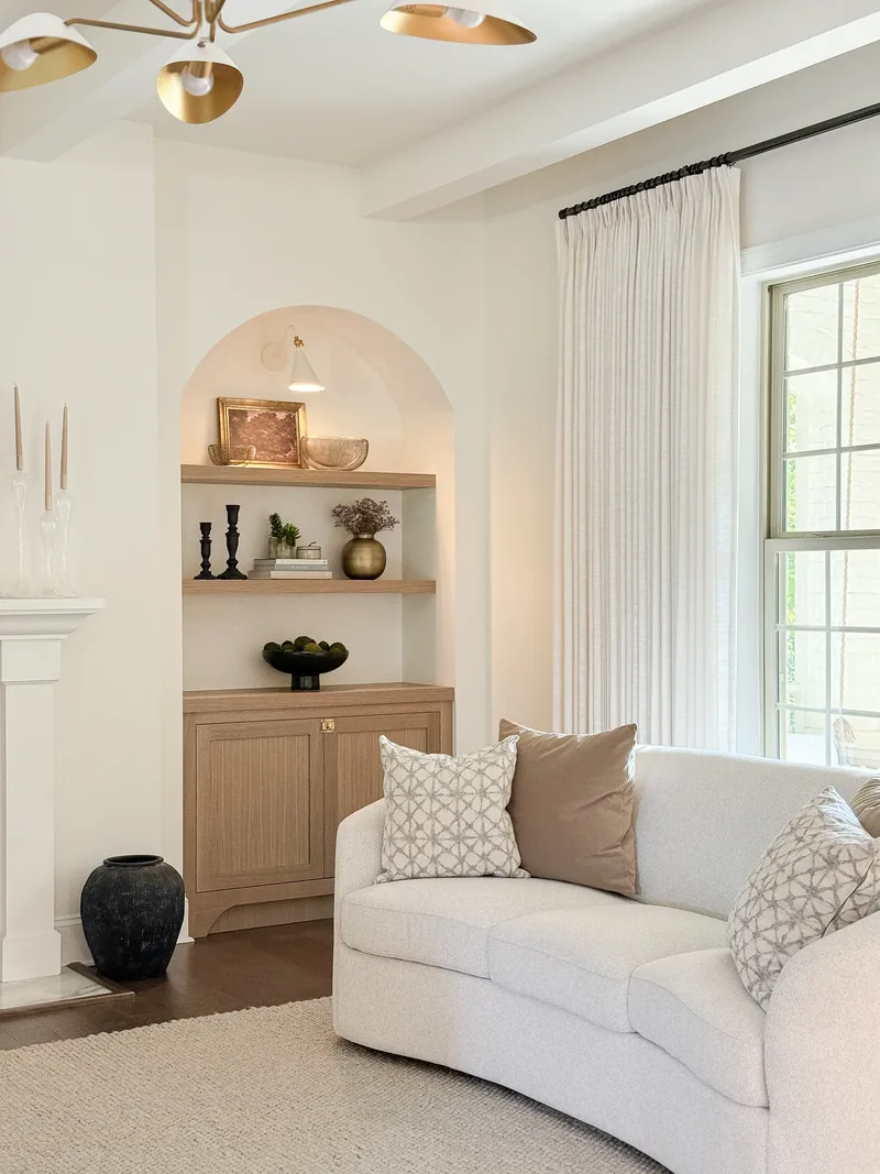 The built-in and sofa from below the chandelier, whose brass arms cross the top of the frame