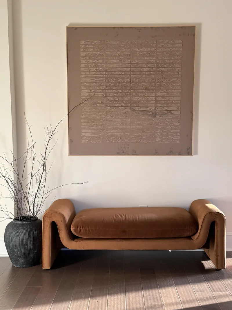 The entry hall squared up, sunlight reaching across the floorboards to the bench and its canvas