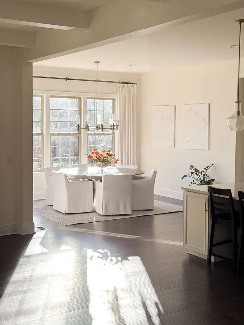 From the kitchen, past a cream island and black counter stool, the table under its chandelier