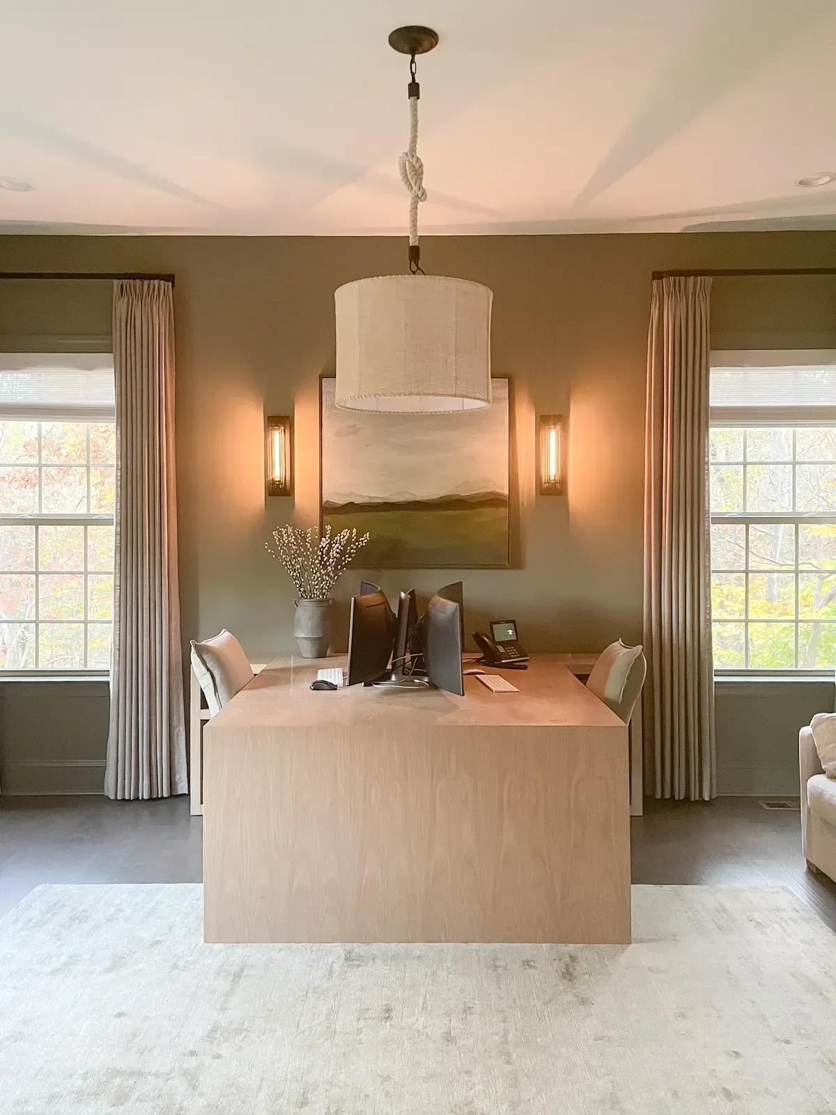 Home office with a pale wood desk, drum pendant and linen drapery to the floor